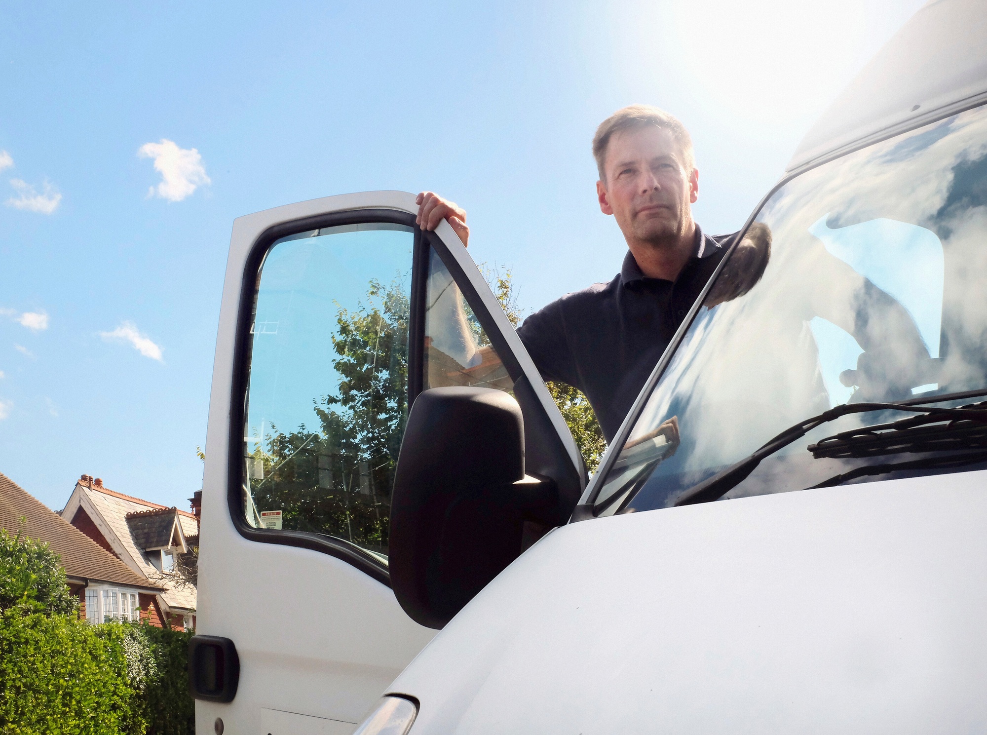 Delivery man looking out from white van on suburban street