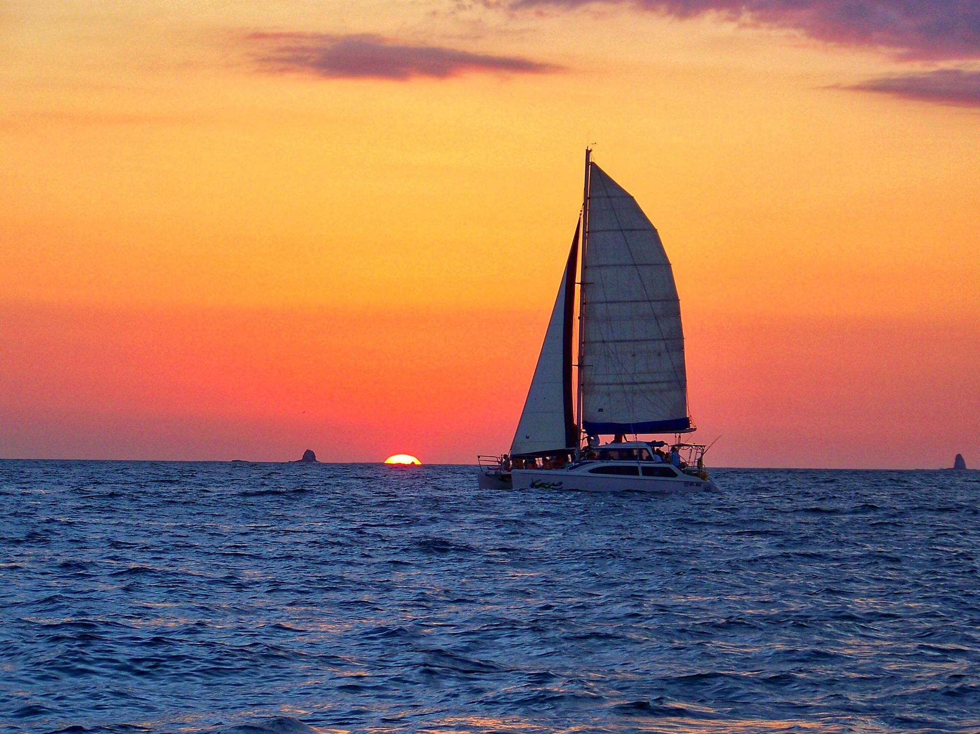 Sun setting over the ocean in Costa Rica as a sail boat passes by